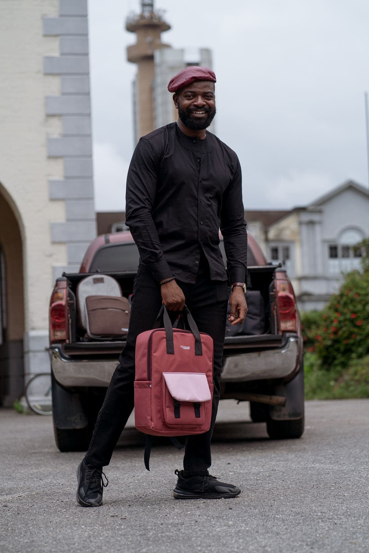 Smiling man holding a crimson flap-top Lightbulb backpack