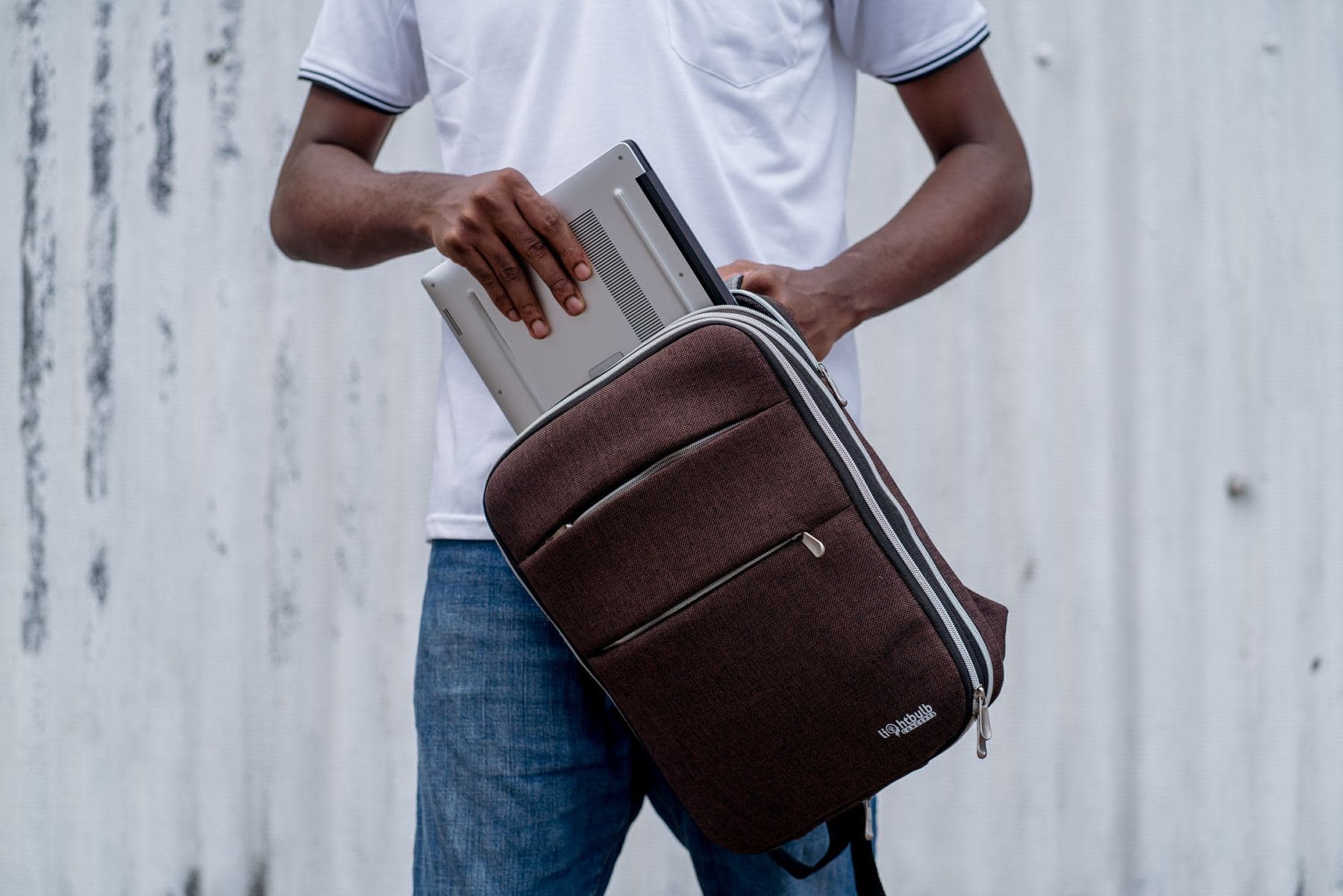 Sliding a laptop into a brown Lightbulb backpack