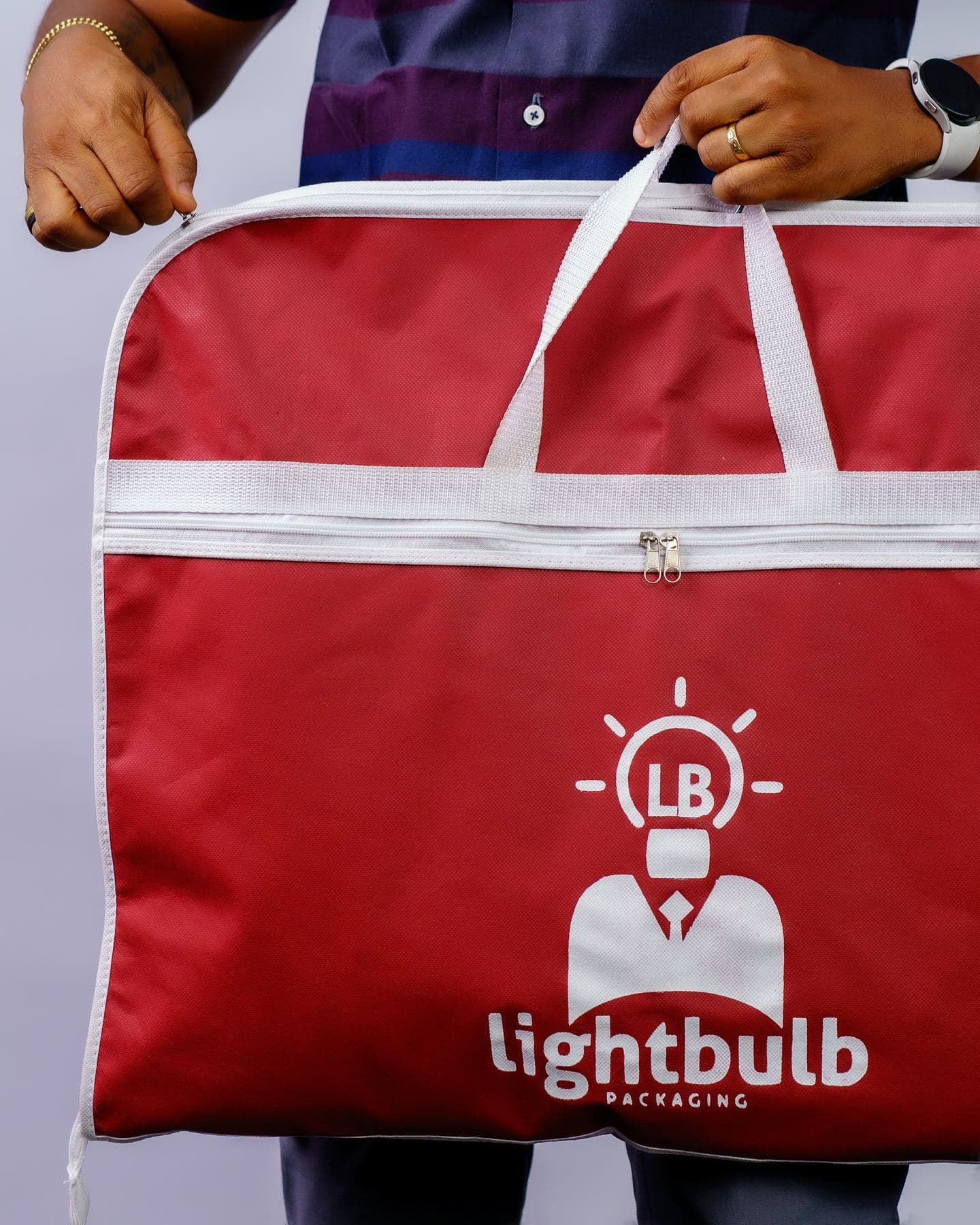 A red branded garment bag made by Lightbulb Packaging